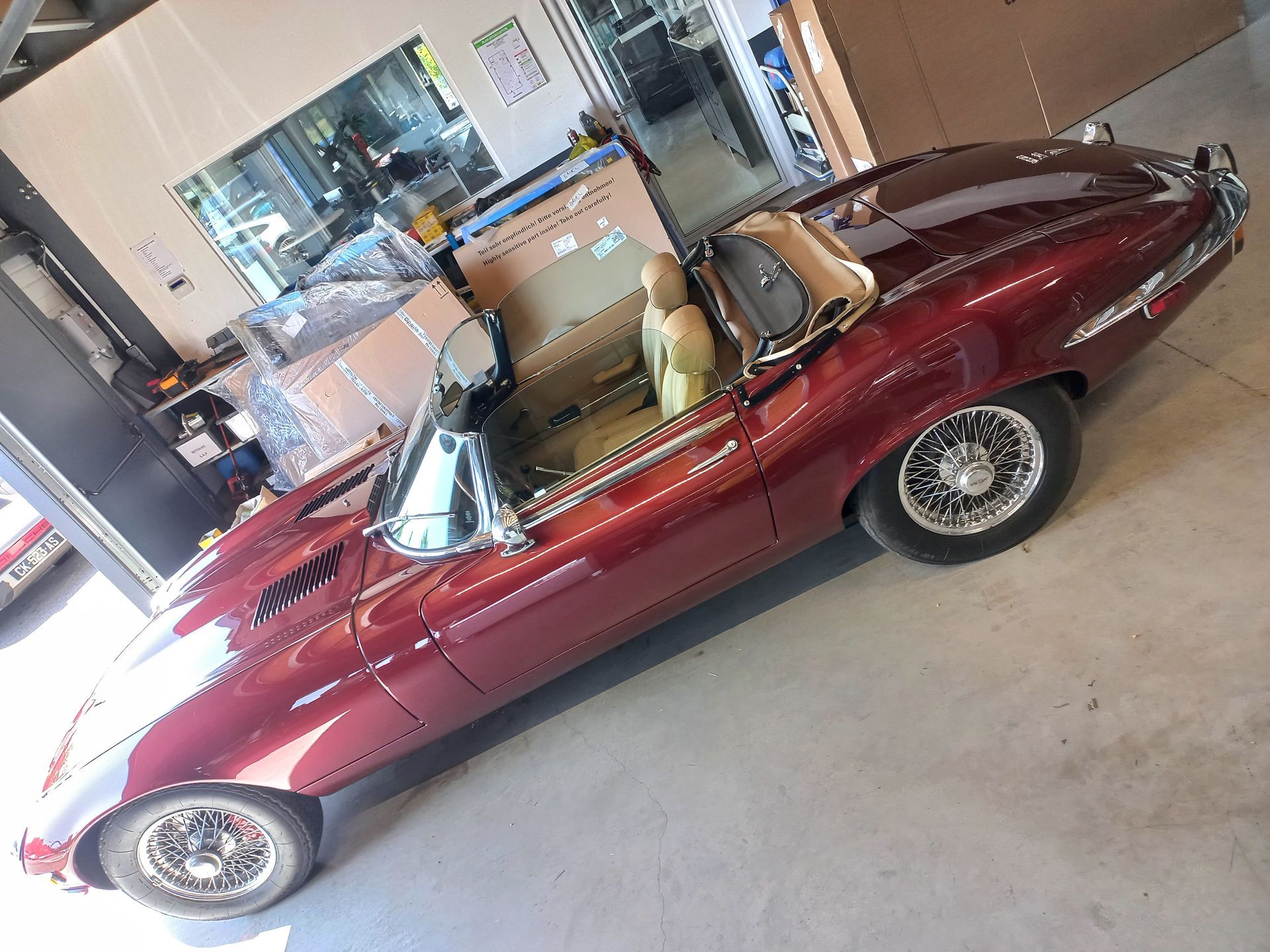 Cabriolet vintage bordeaux dans un garage, intérieur beige et détails chromés.
