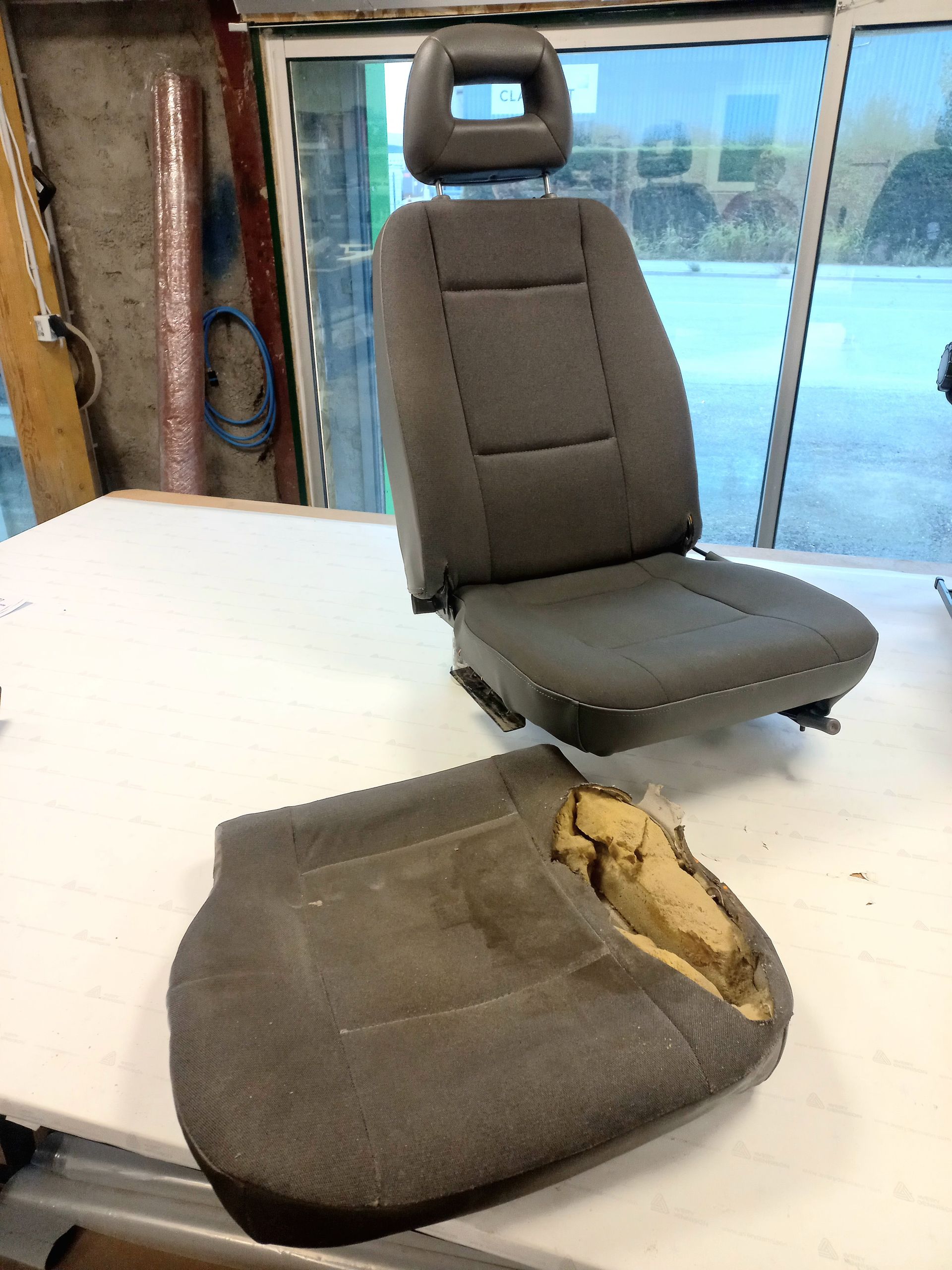 Siège auto et coussin déchiré et détaché sur un établi dans un atelier de garage