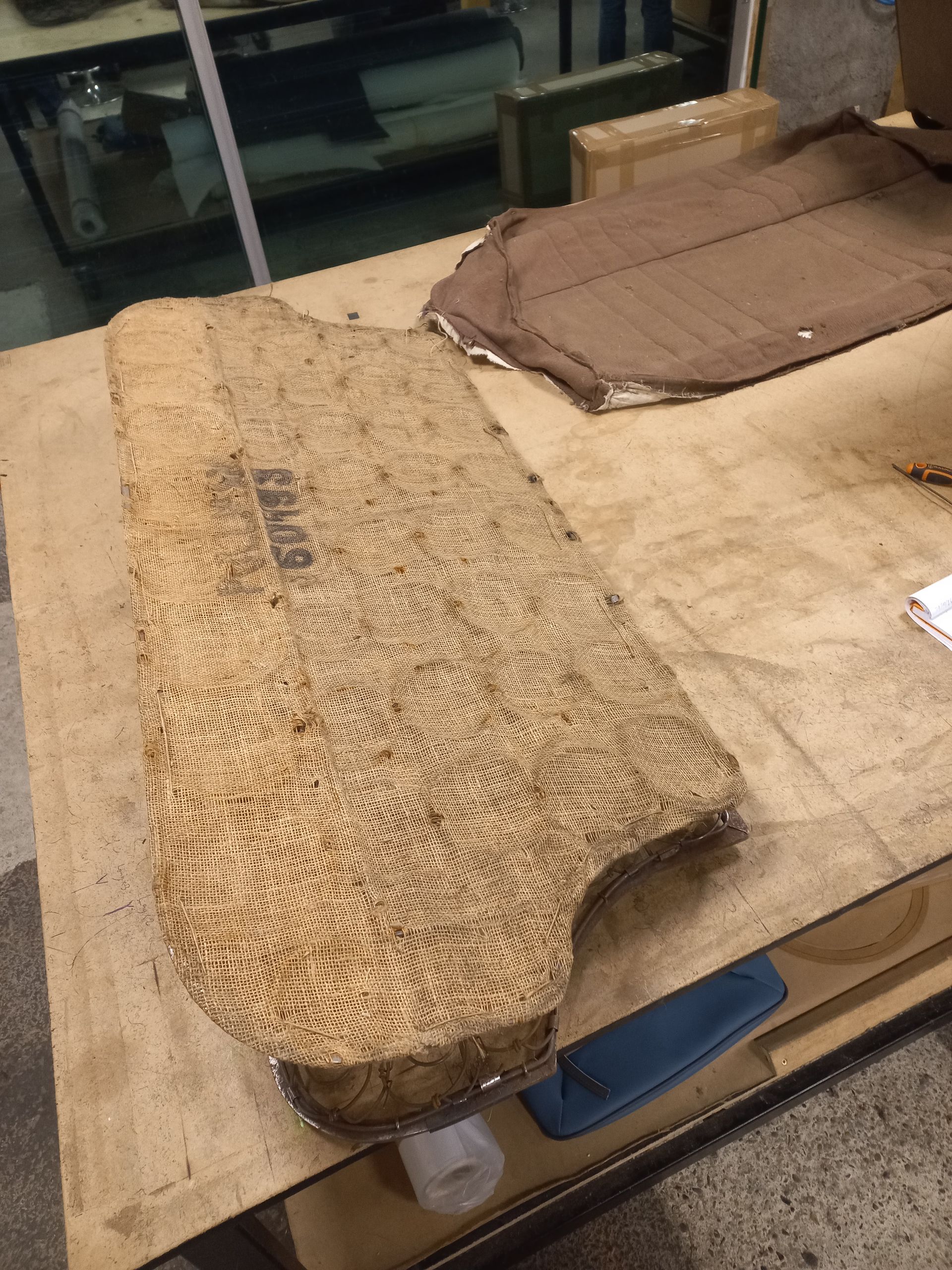 Planche à découper en bois usée sur un établi, avec un torchon marron à côté.