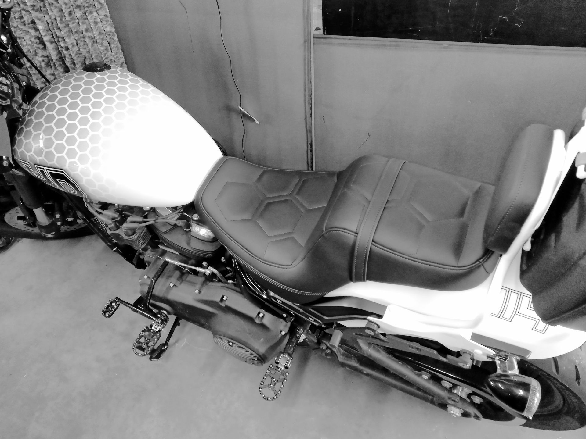 Moto garée à l'intérieur, vue de côté avec réservoir d'essence à motifs et selle à deux niveaux