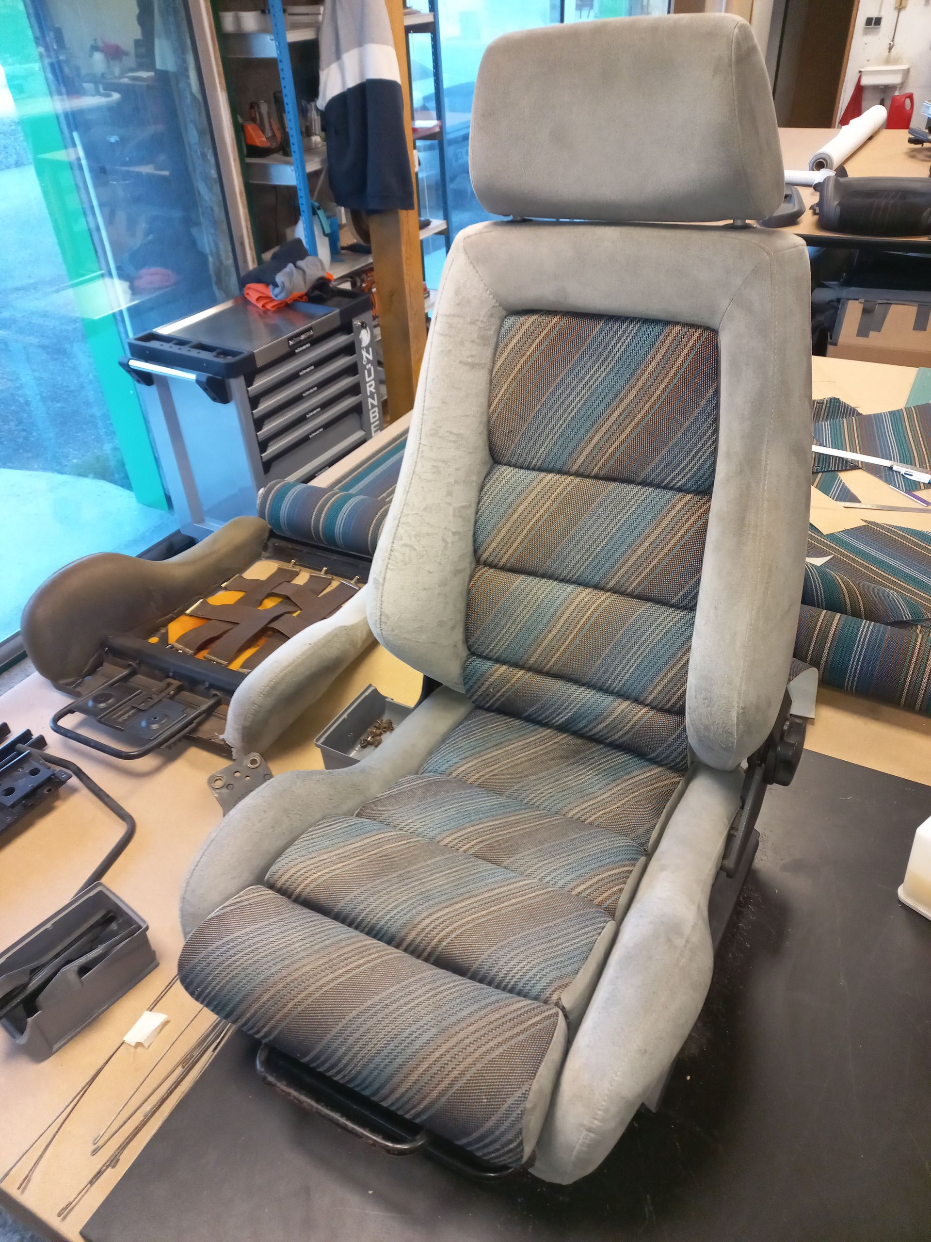 Siège auto rembourré gris et bleu sur un établi dans un atelier de réparation