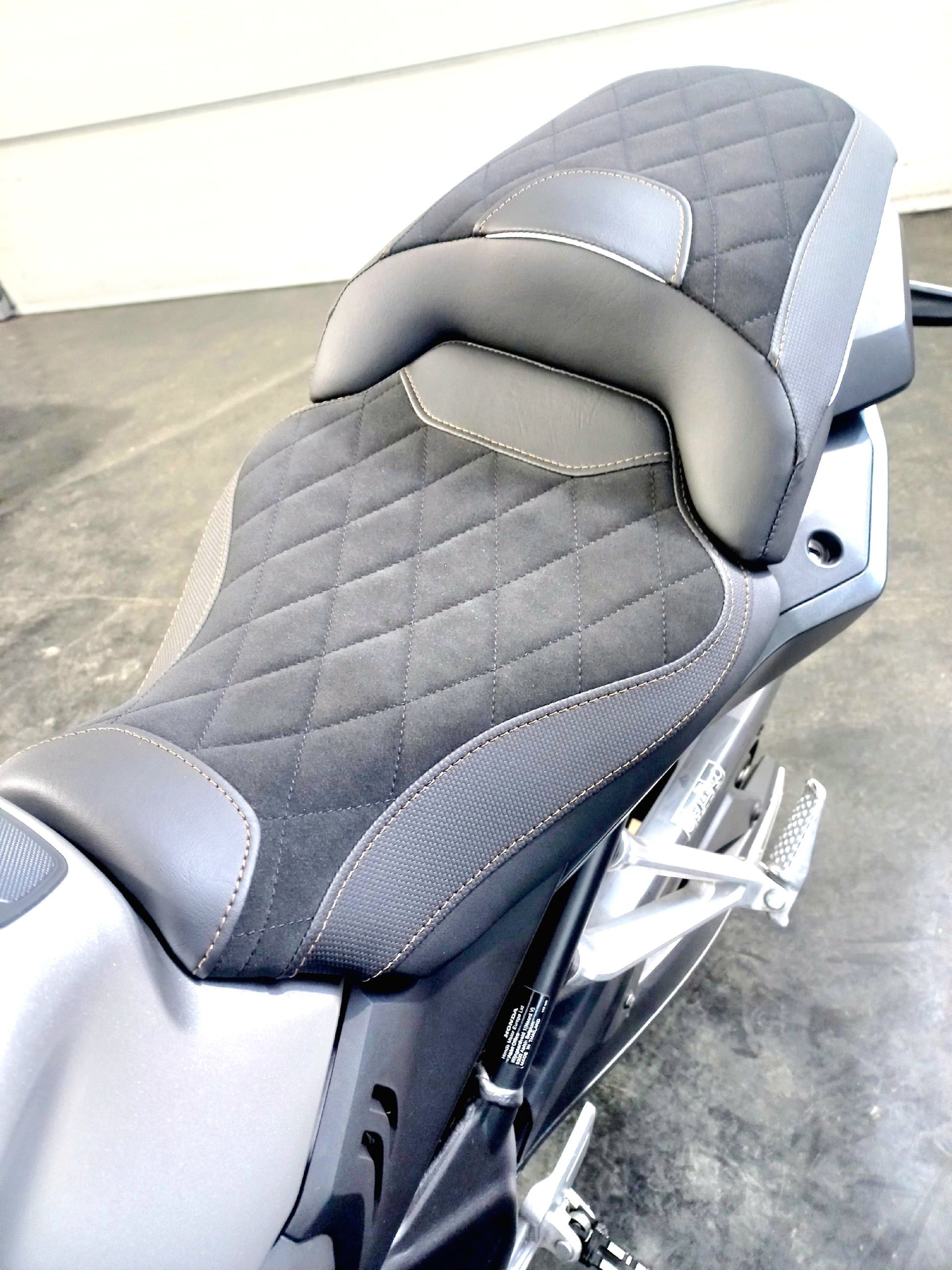Selle de moto matelassée noire, vue de dessus dans un garage.