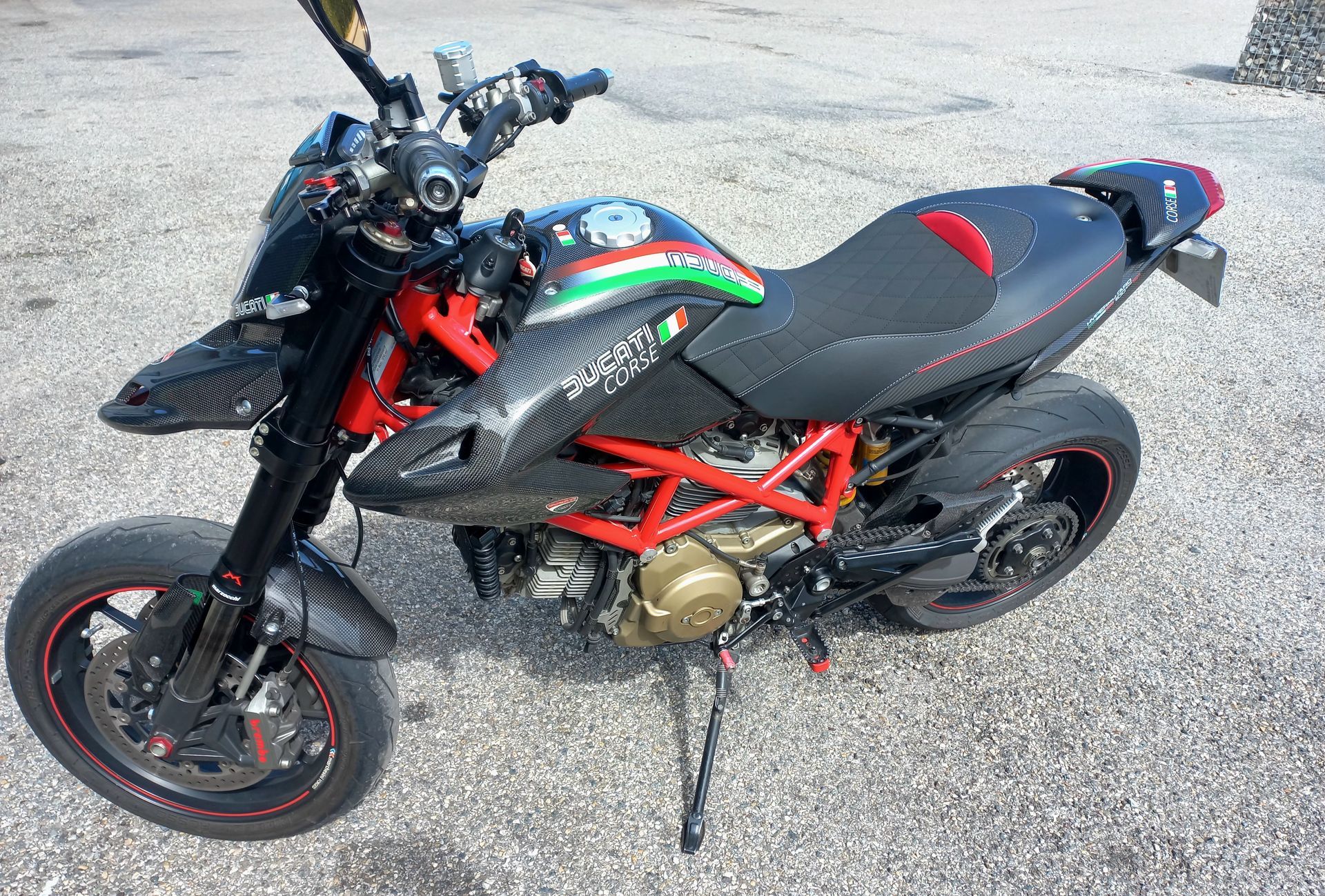 Moto sportive noire à cadre rouge et bande verte garée sur le trottoir, vue de dessus