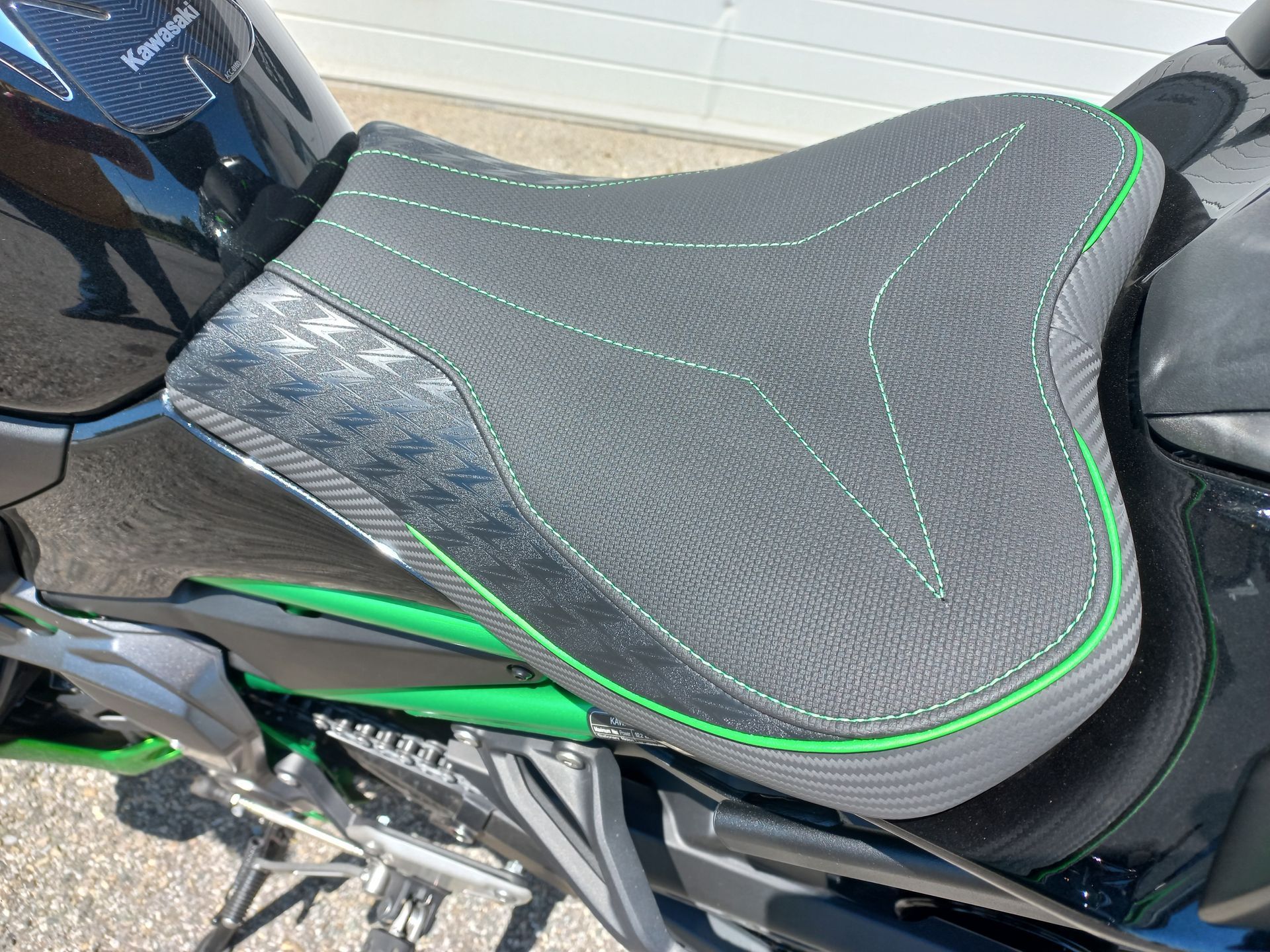 Gros plan sur une selle de moto noire avec surpiqûres et garnitures vertes
