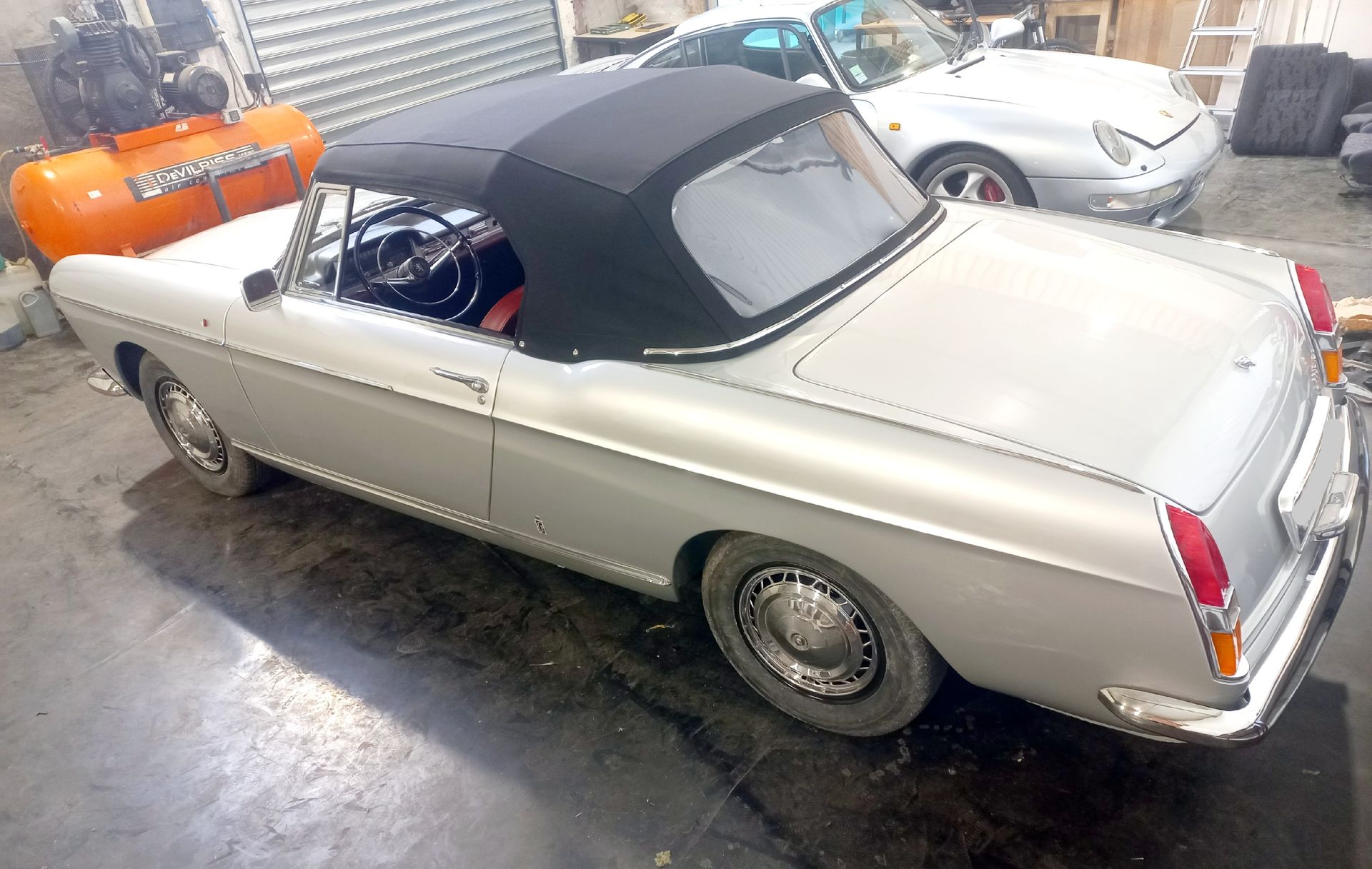 Cabriolet vintage argenté avec capote noire garé dans un garage