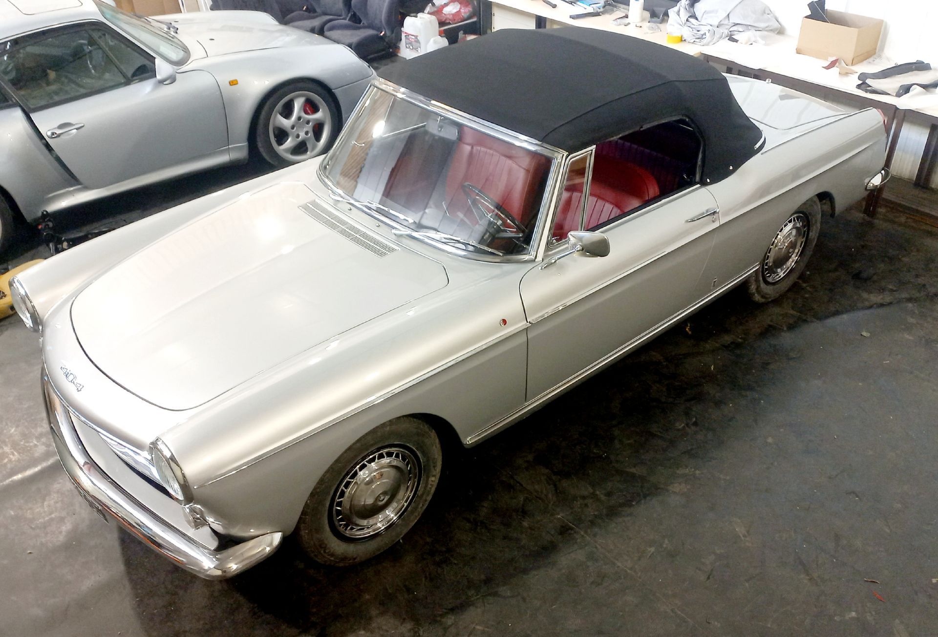 Cabriolet vintage argenté à capote noire garé dans un garage, vu du dessus