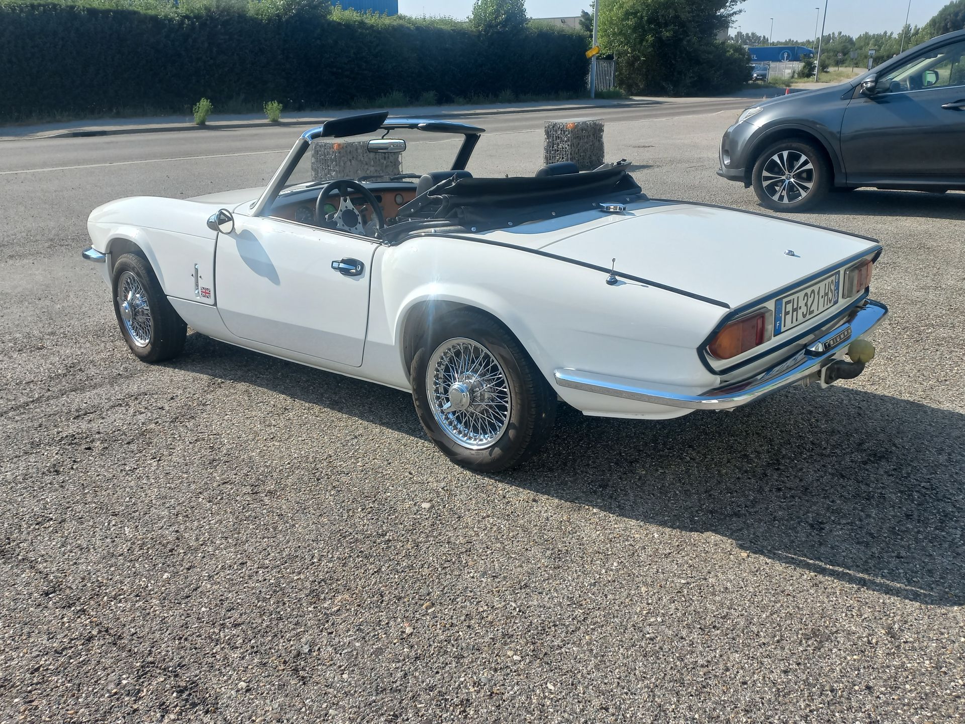 Voiture de sport décapotable blanche vintage garée sur le trottoir sous un ciel ensoleillé