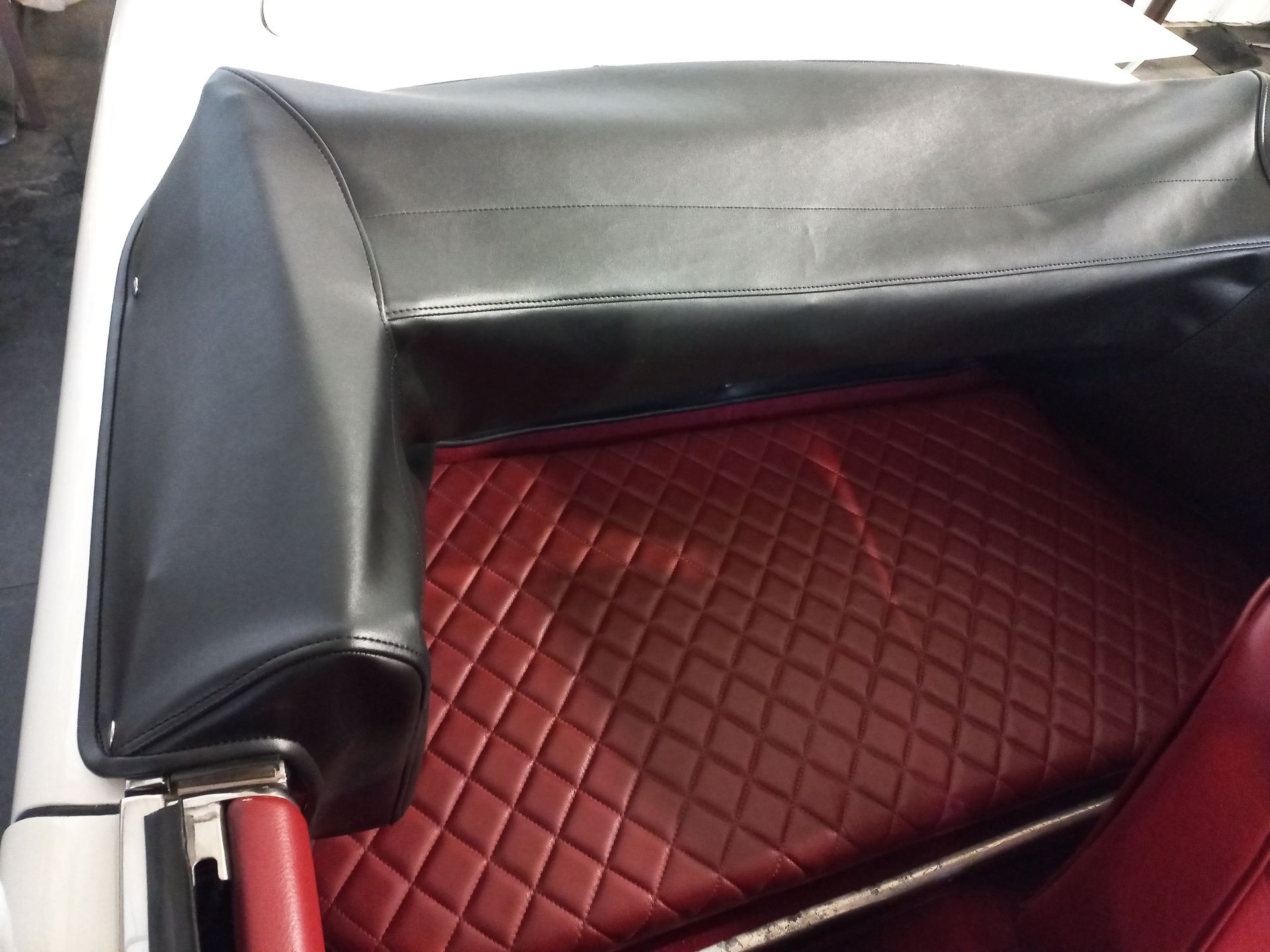 Fauteuil en cuir noir avec coussin d'assise matelassé rouge en losanges