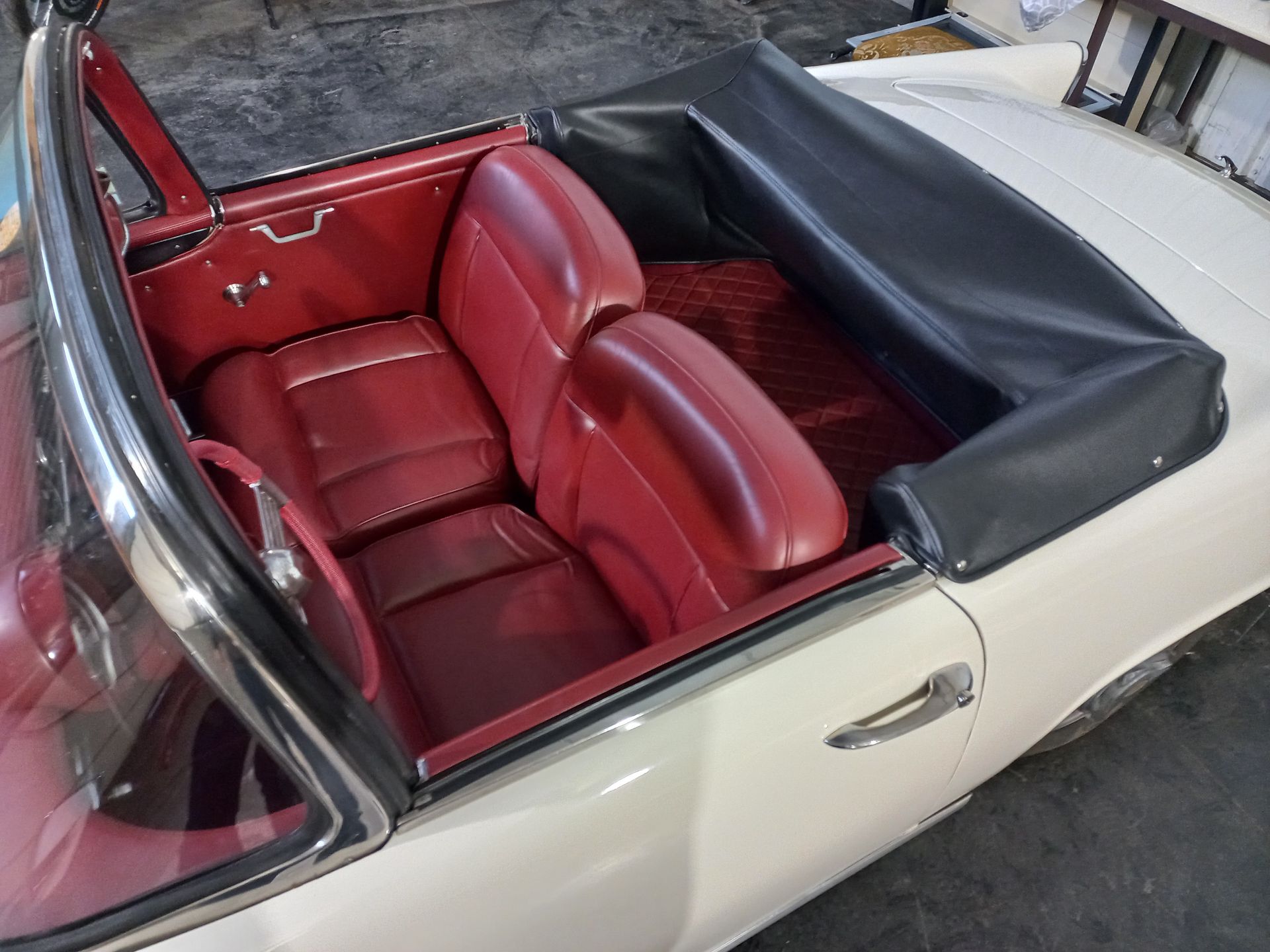 Intérieur de cabriolet en cuir rouge avec capote noire repliée et garnitures extérieures crème