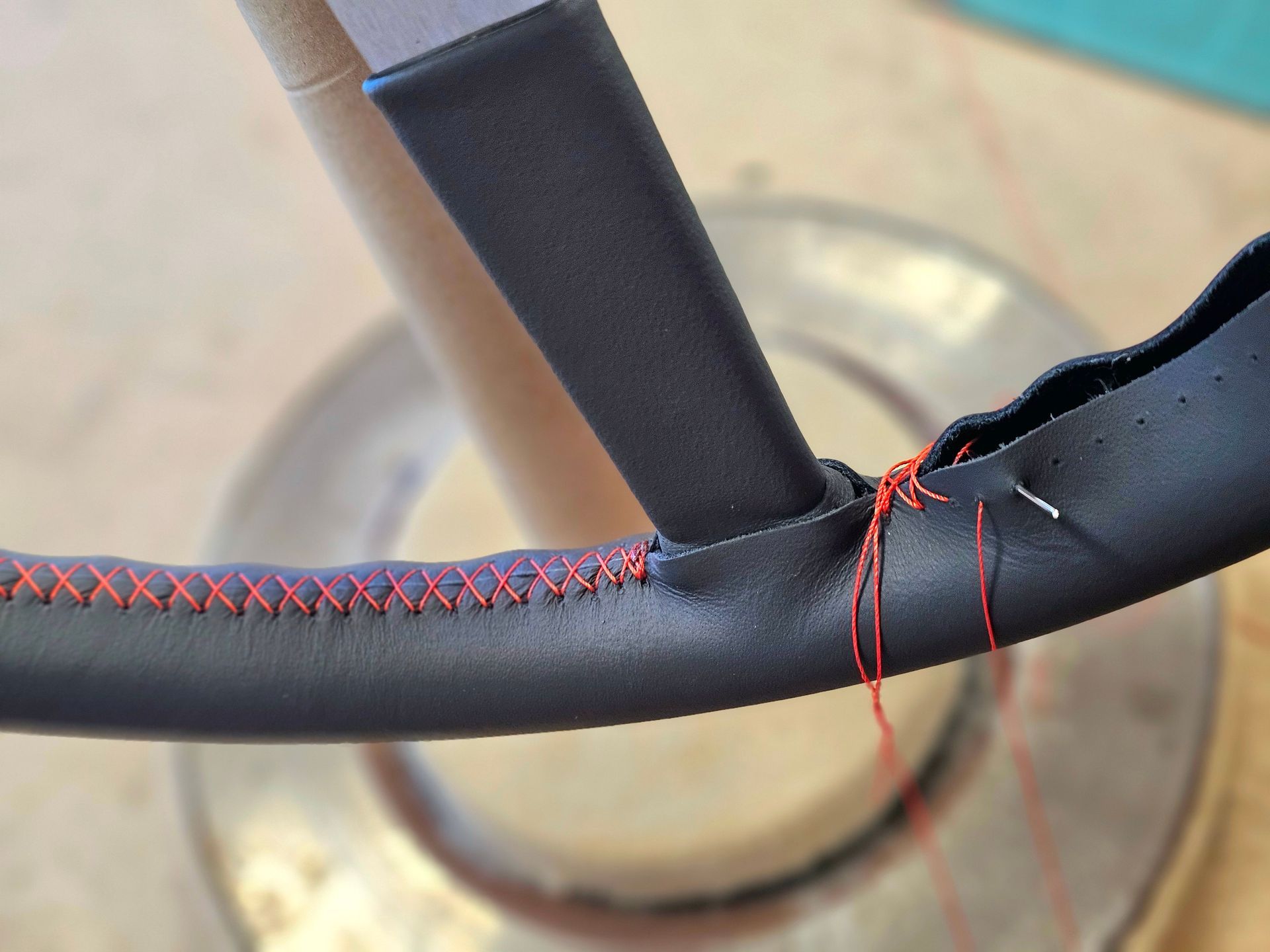 Gros plan sur un cadre de volant noir avec des coutures/fils de réparation rouges le long d'une couture.