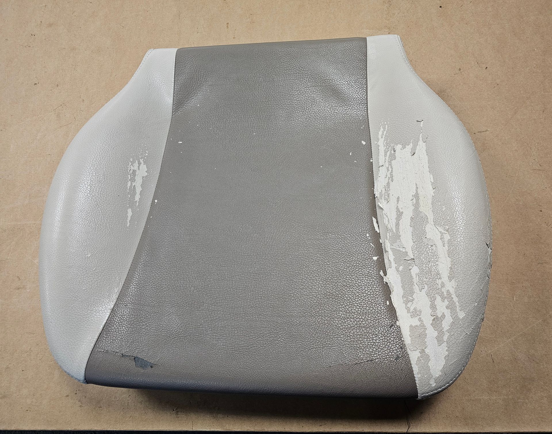 Objet gris rembourré avec des côtés blancs sur une surface beige