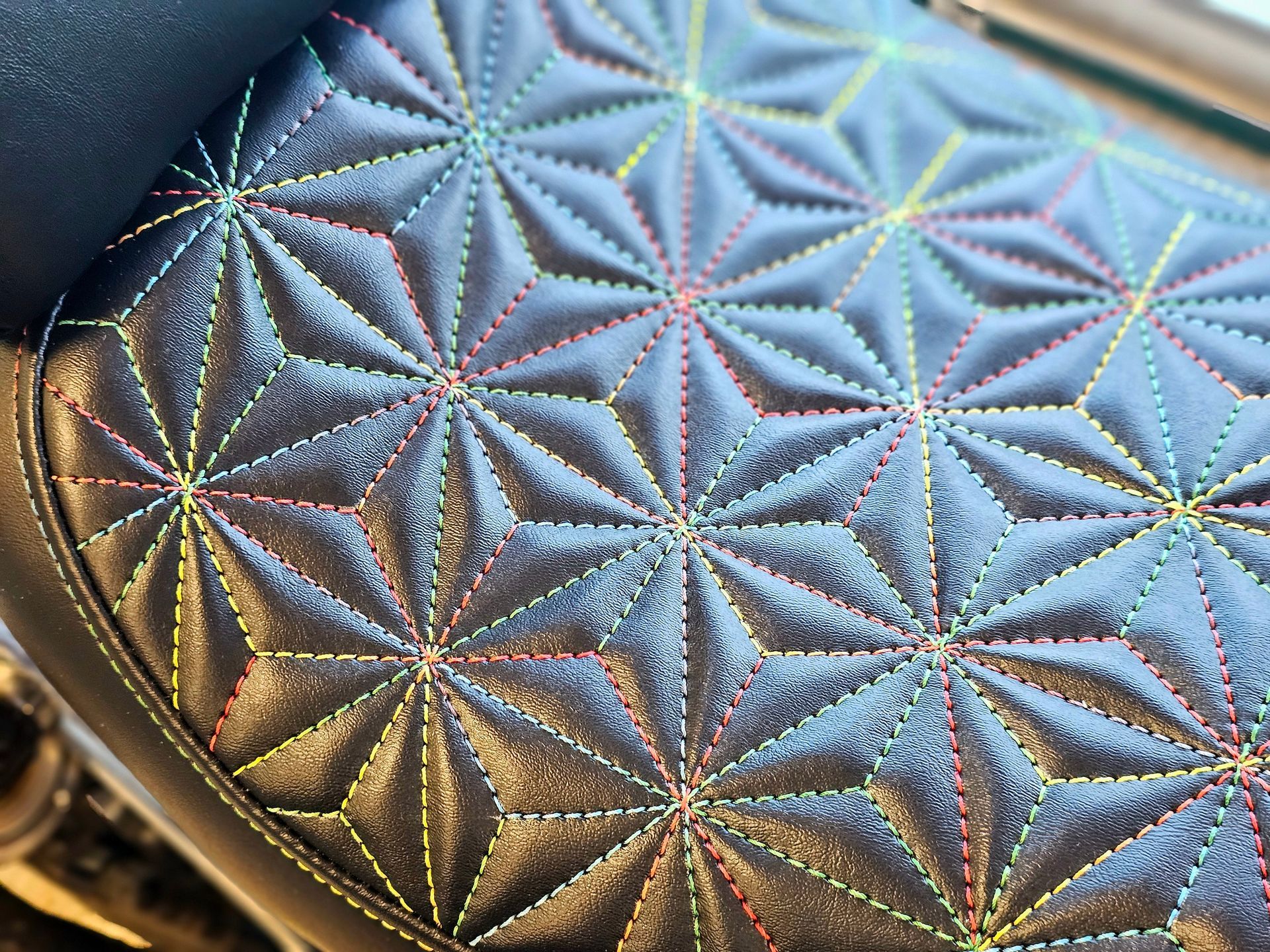 Gros plan sur une surface matelassée métallique aux motifs irisés en forme d'étoile et aux tons bleu-gris.