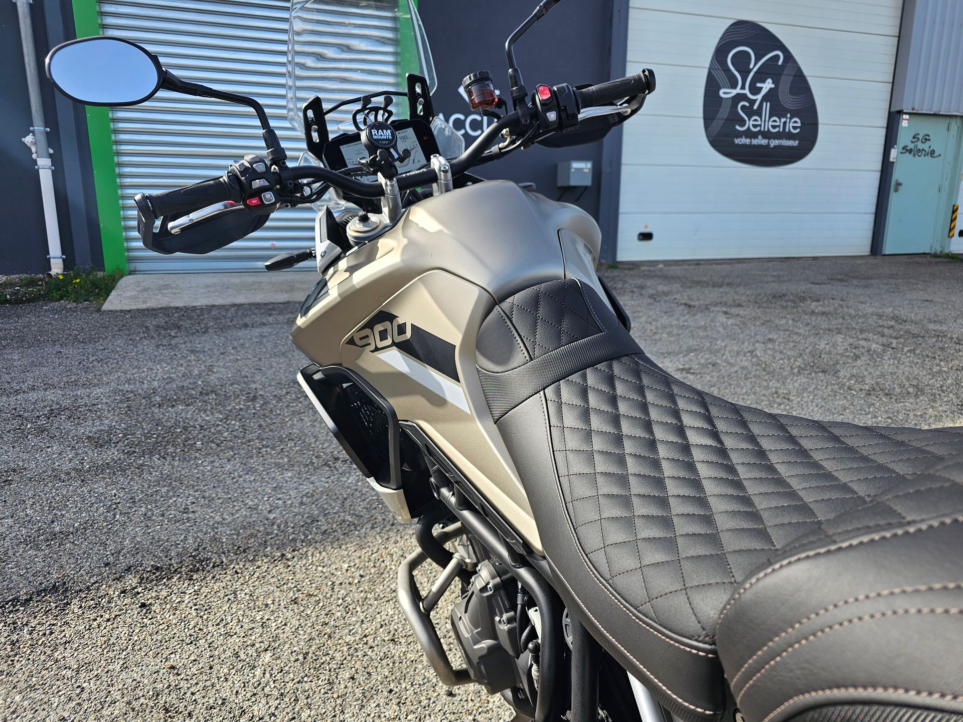 Selle et guidon de moto devant un garage avec une enseigne sur le mur