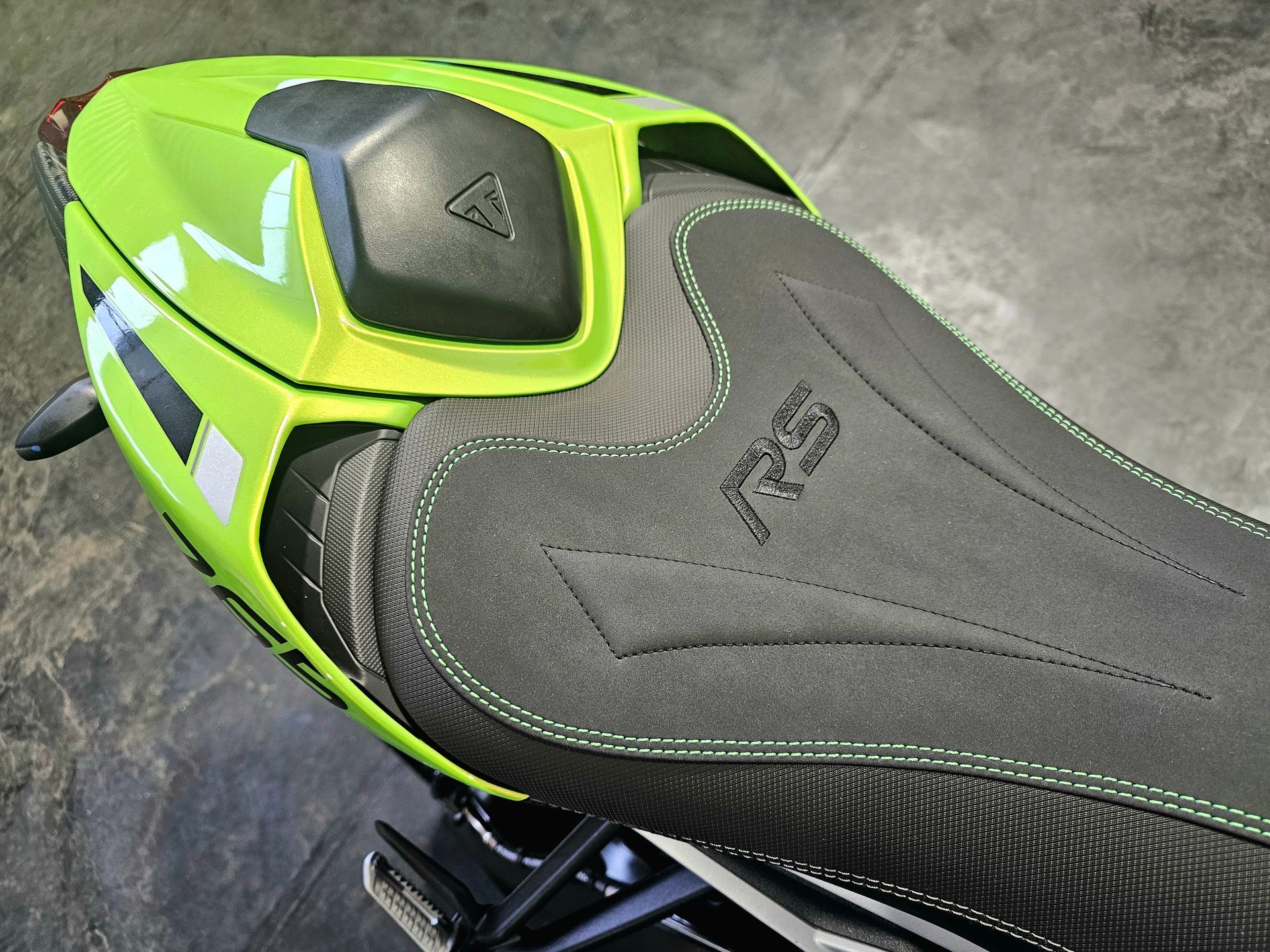 Selle et panneau arrière de moto vert fluo et noir sur un sol en béton