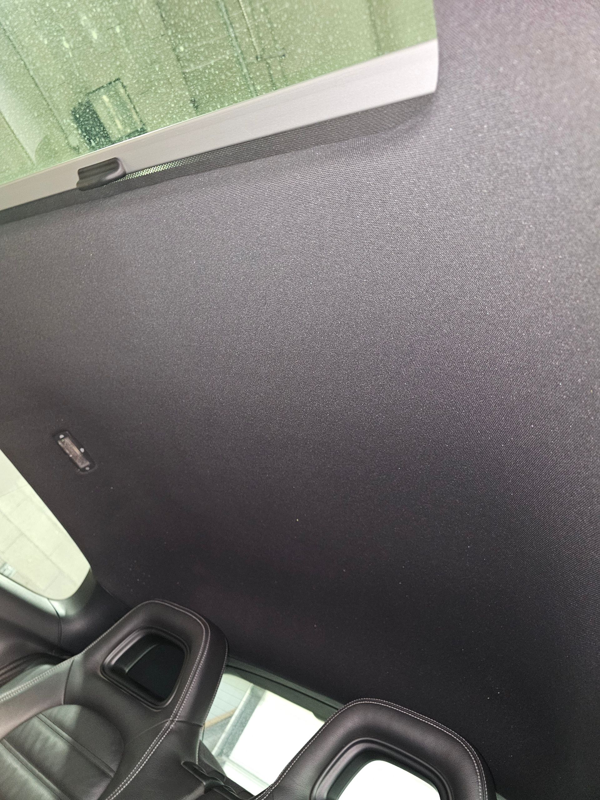 Intérieur noir d'une voiture avec toit ouvrant, vu du dessus des deux sièges avant