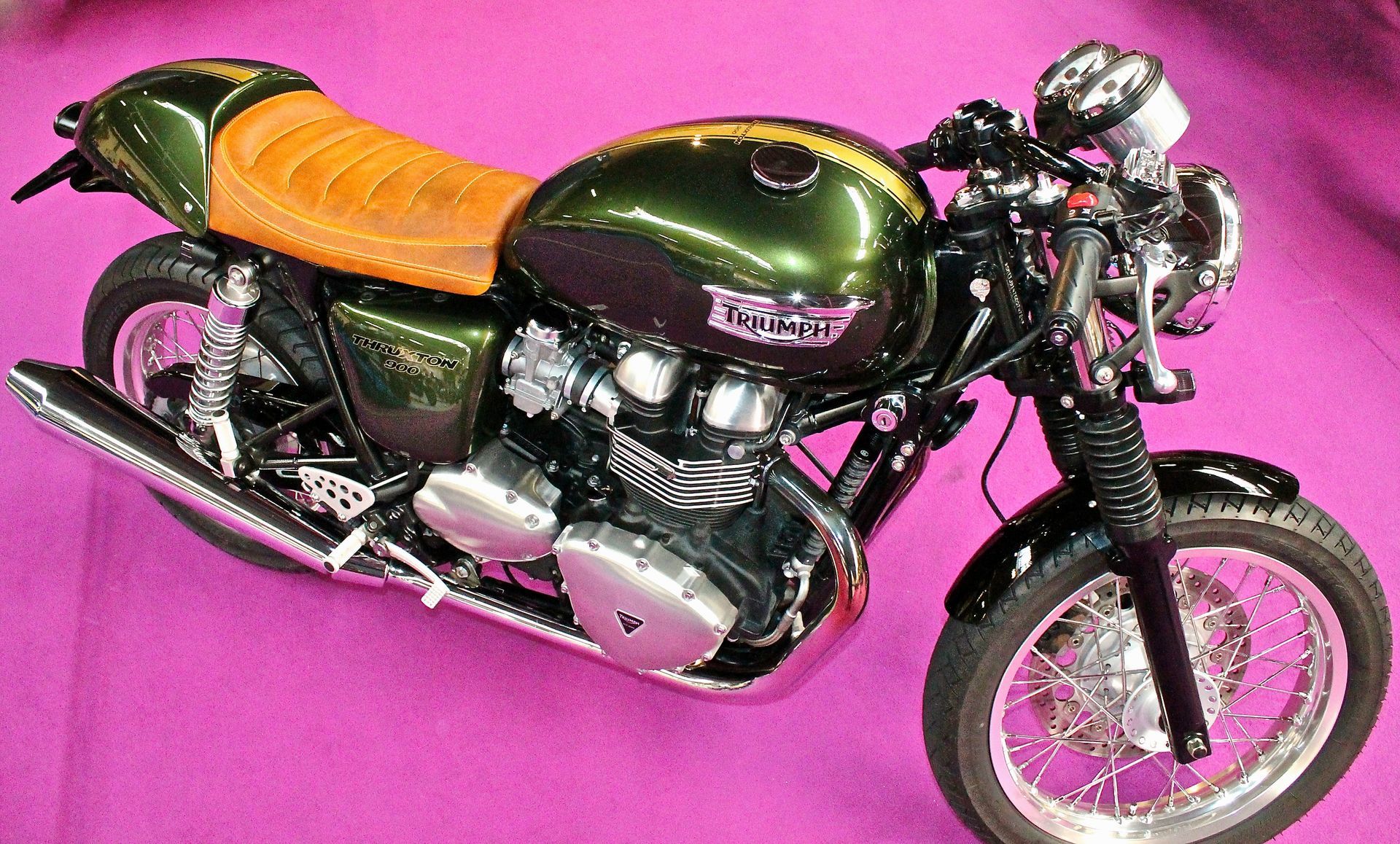 Moto verte avec selle orange sur fond rose