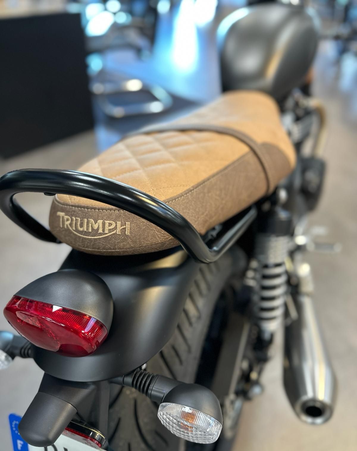 Gros plan sur une selle et un feu arrière de moto Triumph beige dans un showroom