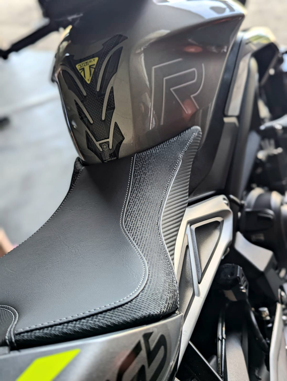 Gros plan sur une selle et un carénage de moto noirs avec des accents jaune fluo et des graphismes rouges