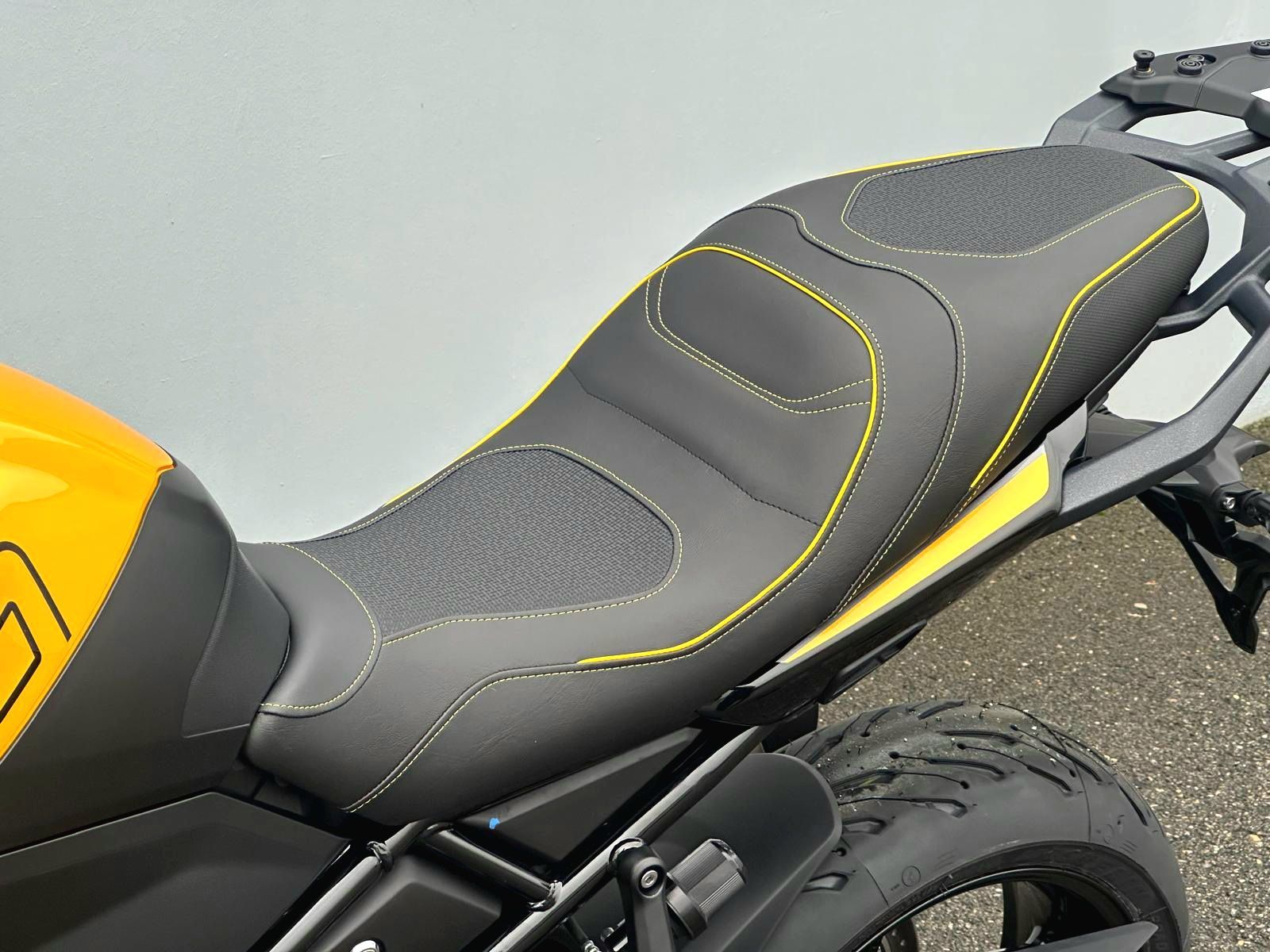 Gros plan sur une selle de moto noire avec des surpiqûres jaunes et un réservoir d'essence jaune