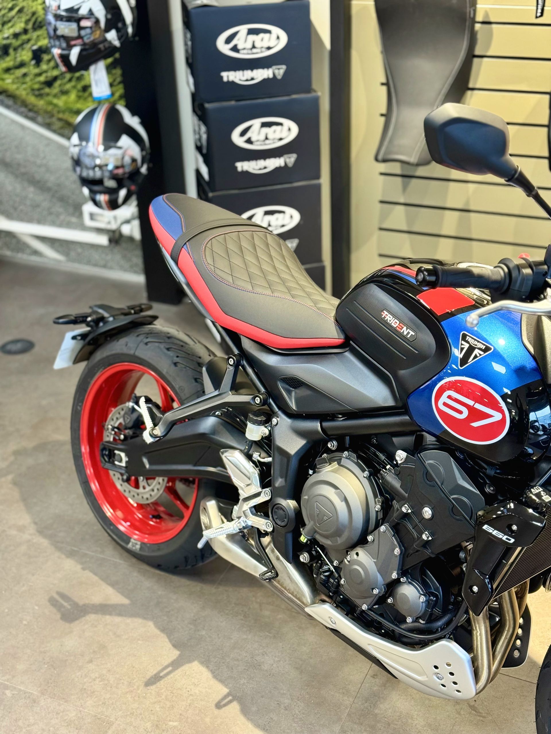 Moto de sport bleue et noire à jantes rouges garée à côté d'un présentoir de pneus à l'intérieur.