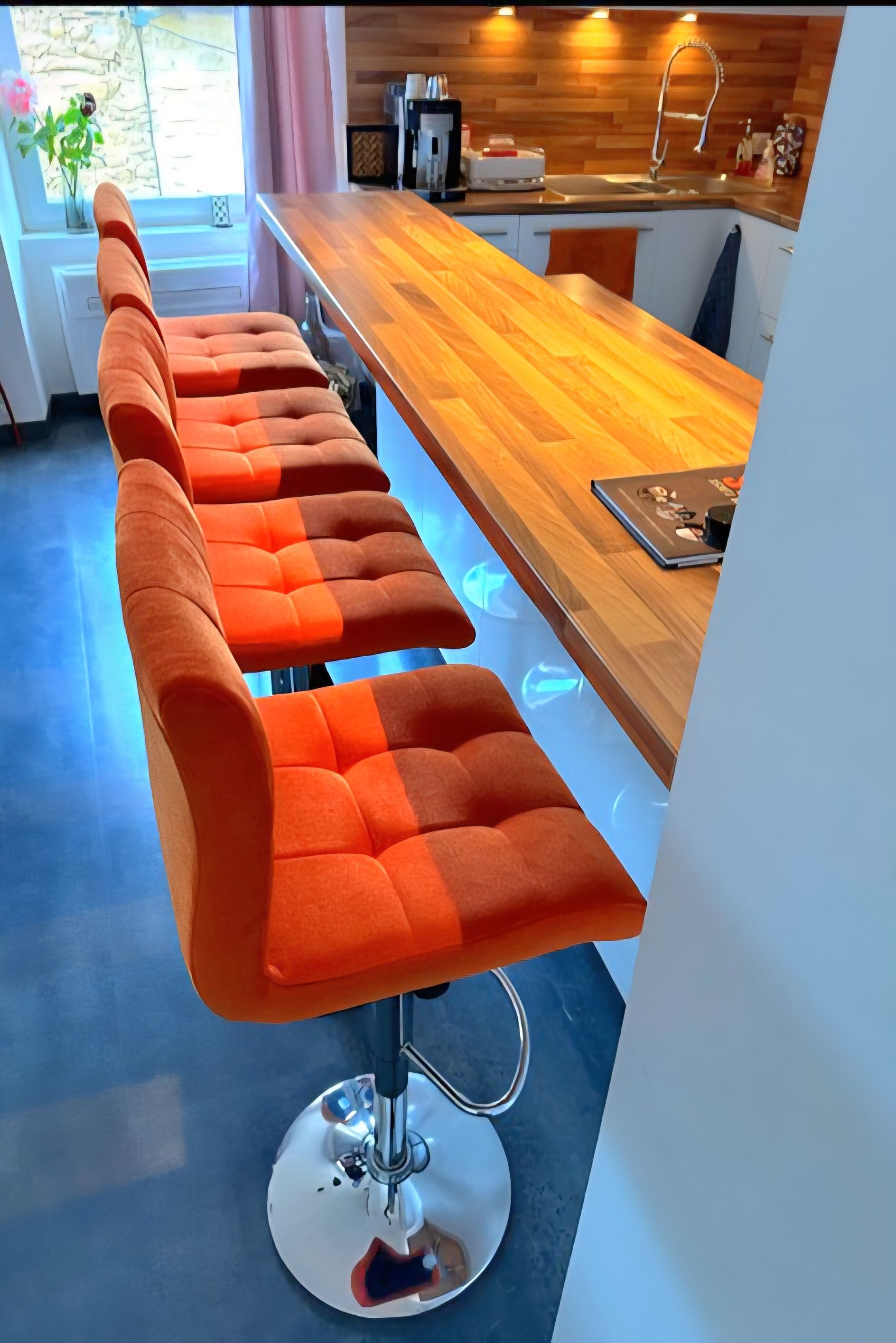 Îlot de cuisine moderne avec trois tabourets de bar orange et un comptoir en bois