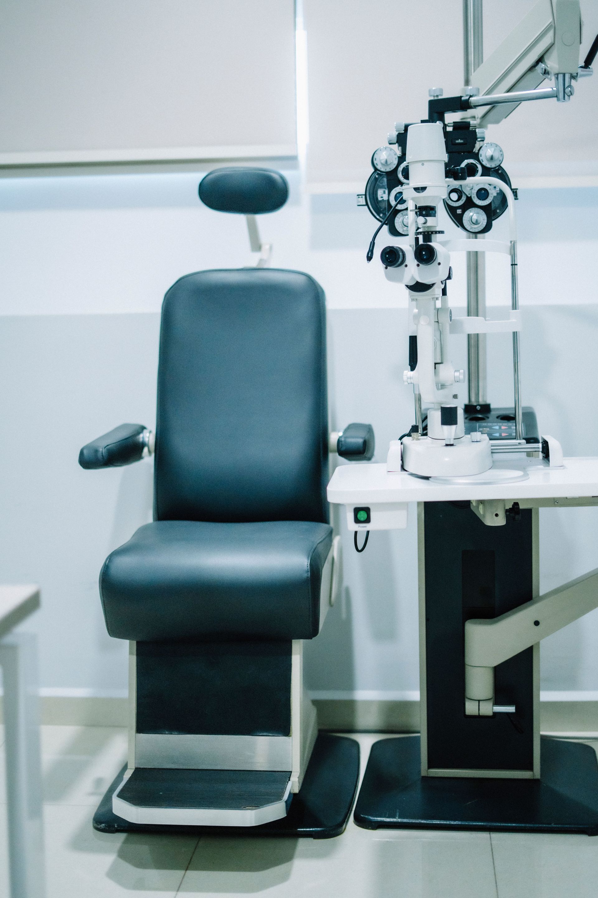 Fauteuil d'examen ophtalmologique à côté d'un phoroptère dans une clinique d'optique lumineuse