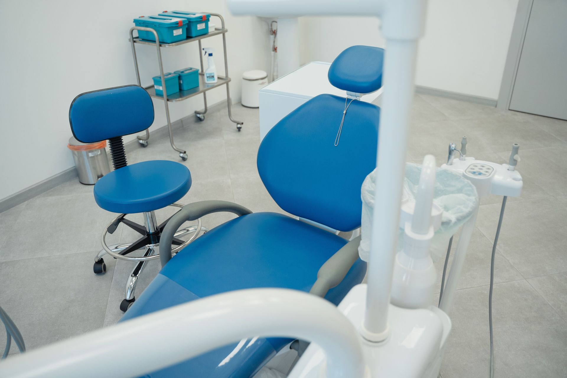 Fauteuil et tabouret dentaires bleus dans une salle d'examen propre équipée de matériel médical