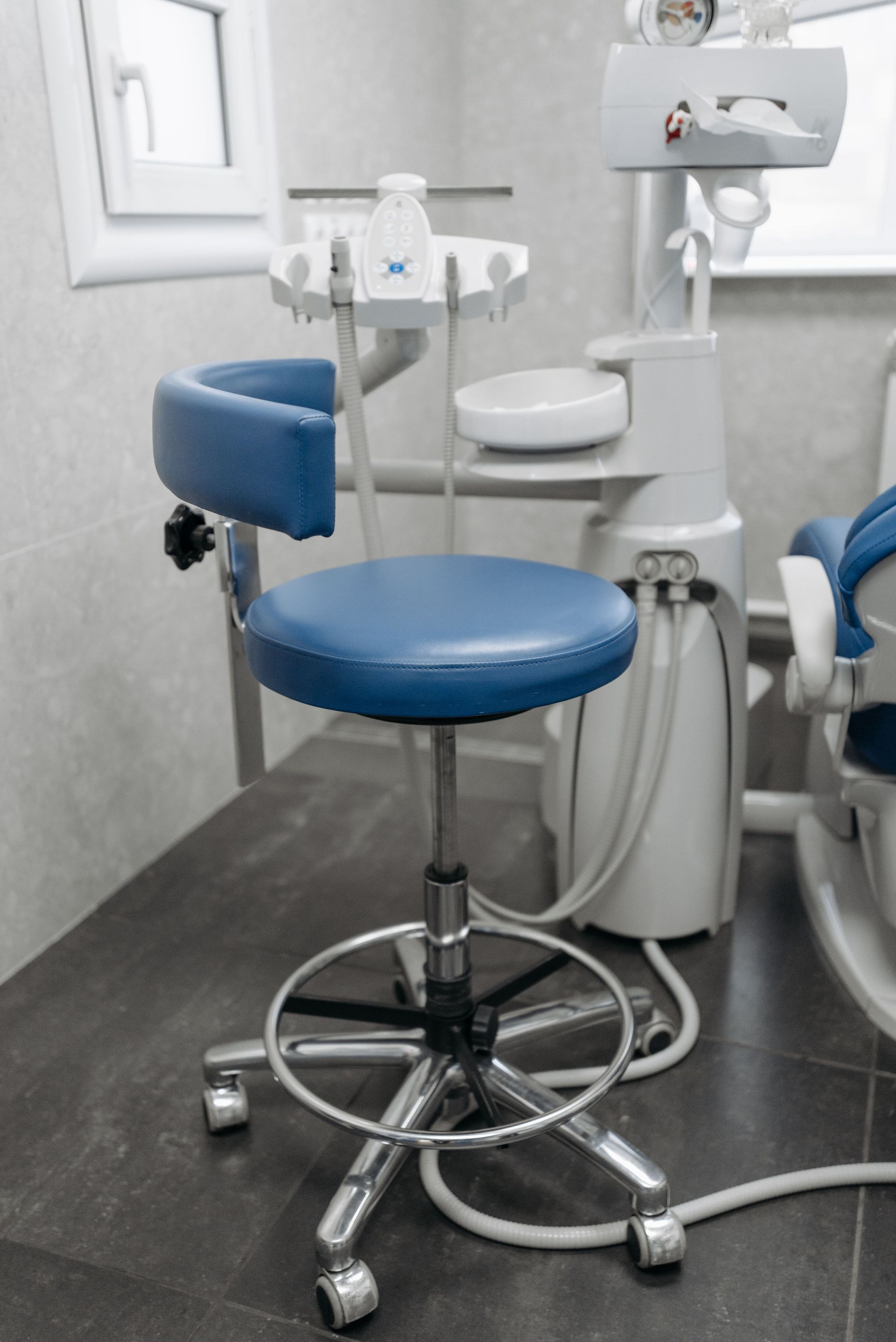 Fauteuil de dentiste bleu et tabouret à roulettes dans une salle d'examen dentaire propre