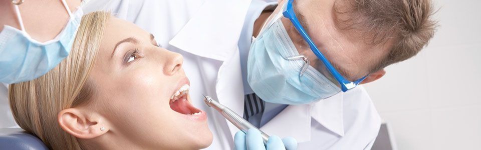Dentista examinando la boca abierta de un paciente en una clínica luminosa.