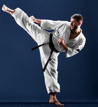 Practicante de karate con uniforme blanco, cinturón negro, ejecutando una patada alta, fondo azul.