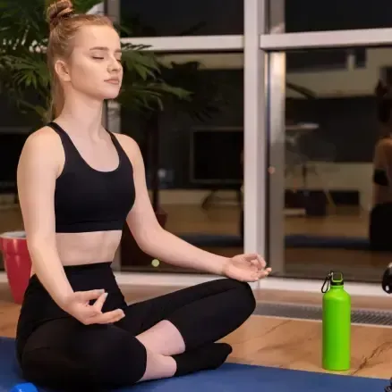 Mujer en ropa deportiva estirando la pierna en el gimnasio.