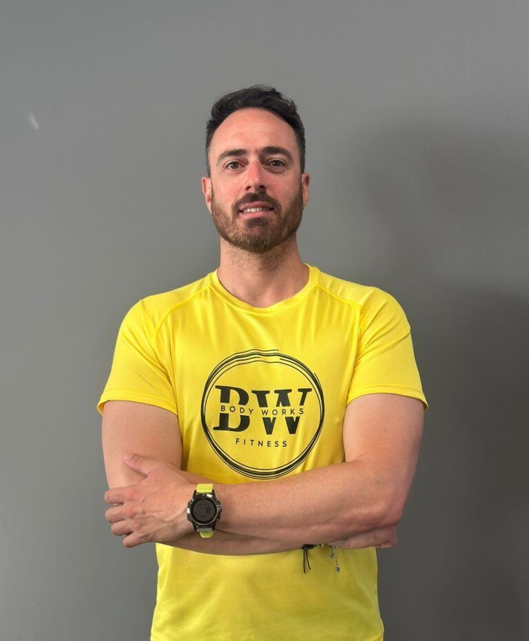 Hombre con los brazos cruzados, con camiseta amarilla con el logo de 