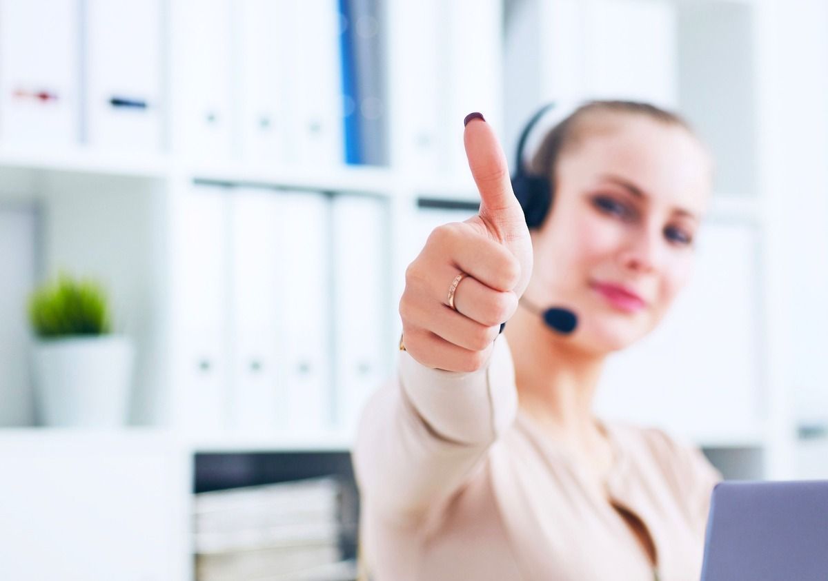 Una mujer que lleva auriculares y un micrófono está haciendo un gesto de aprobación con el pulgar hacia arriba.