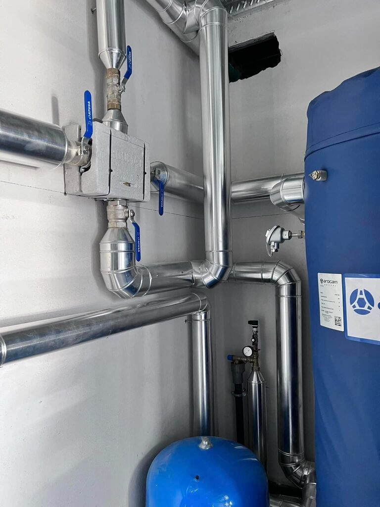 Una habitación llena de muchas tuberías y un tanque azul.