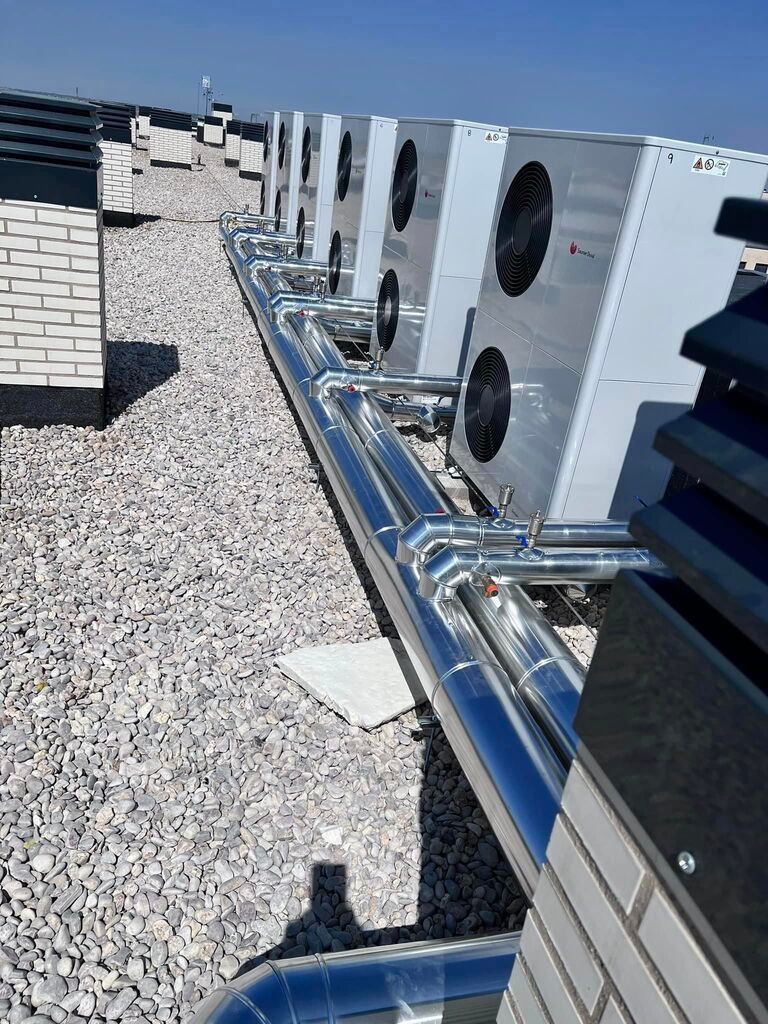 Una fila de aparatos de aire acondicionado están alineados en el techo de un edificio.