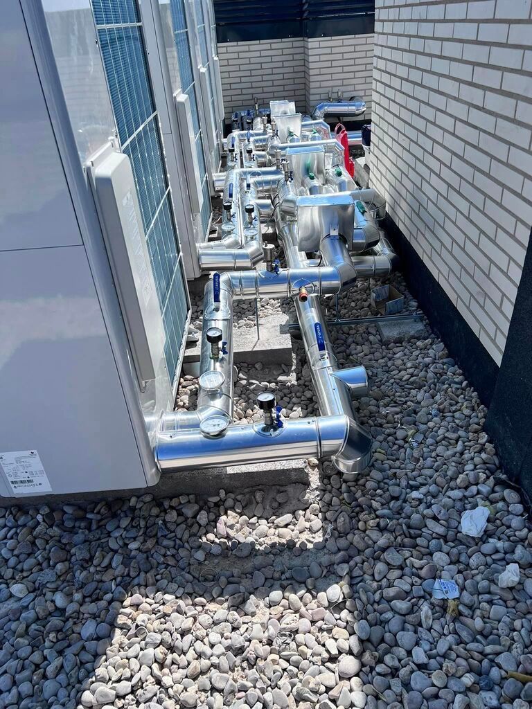 Una hilera de tuberías colocadas encima de una pila de rocas al lado de un edificio.