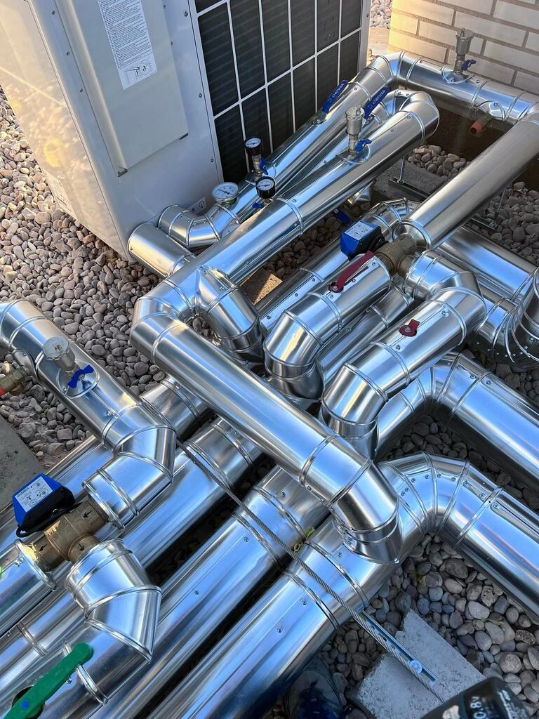 Un montón de tubos de metal están junto a un edificio.