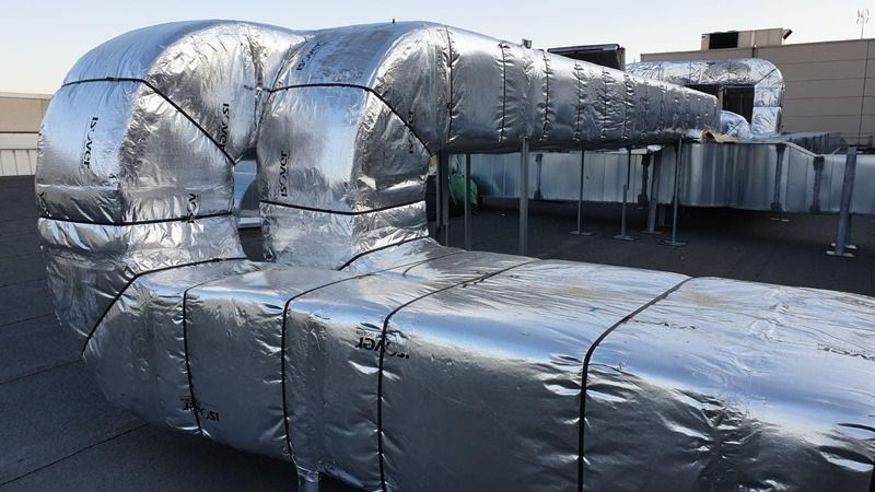 Un conducto grande está envuelto en papel de aluminio en el techo de un edificio.