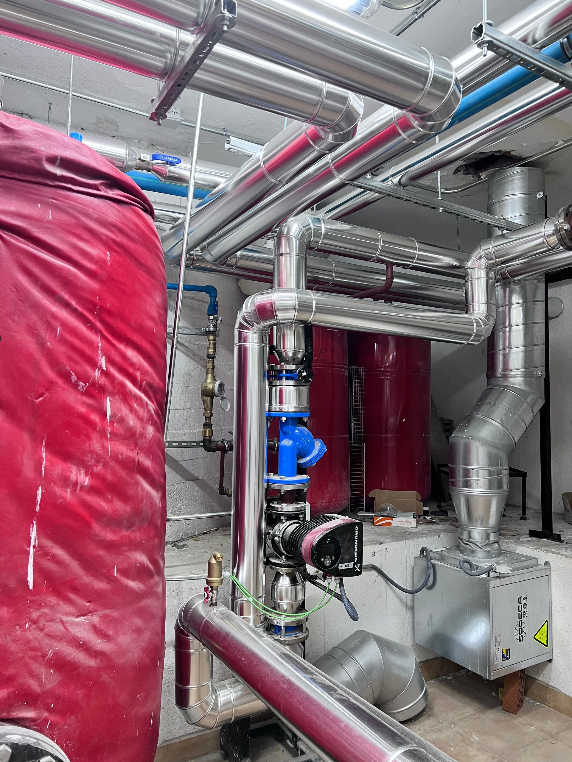 Una habitación llena de muchas tuberías y un tanque rojo.
