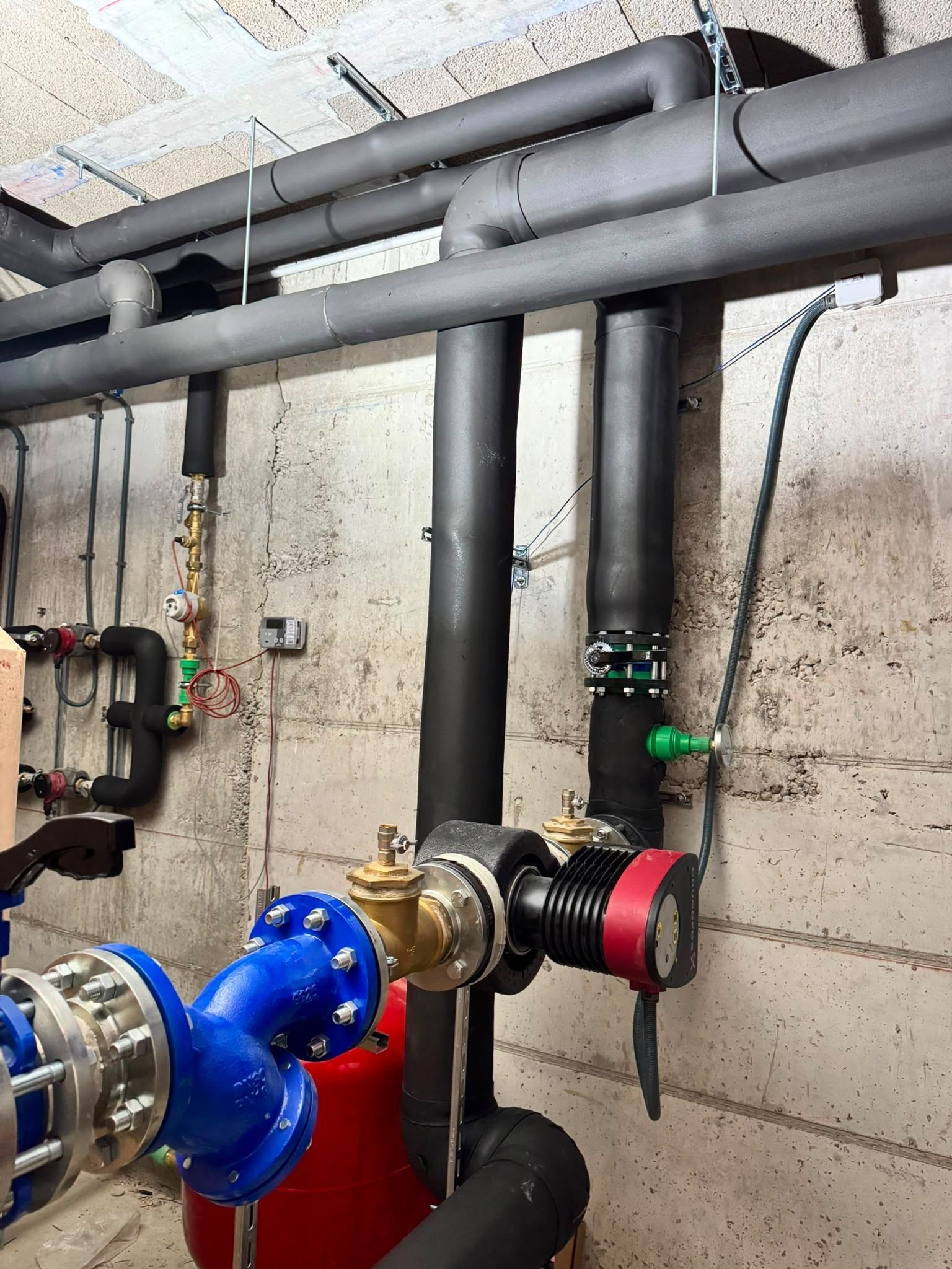 Tuberías industriales y válvulas con accesorios azules y negros en una sala de servicios