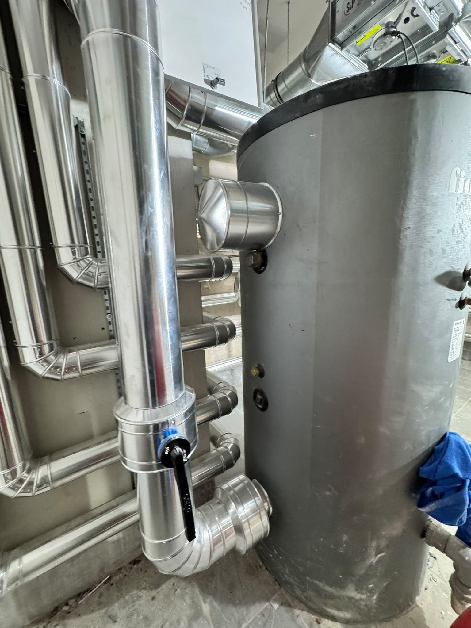 Tuberías industriales conectadas a un gran tanque gris en una sala de servicios técnicos