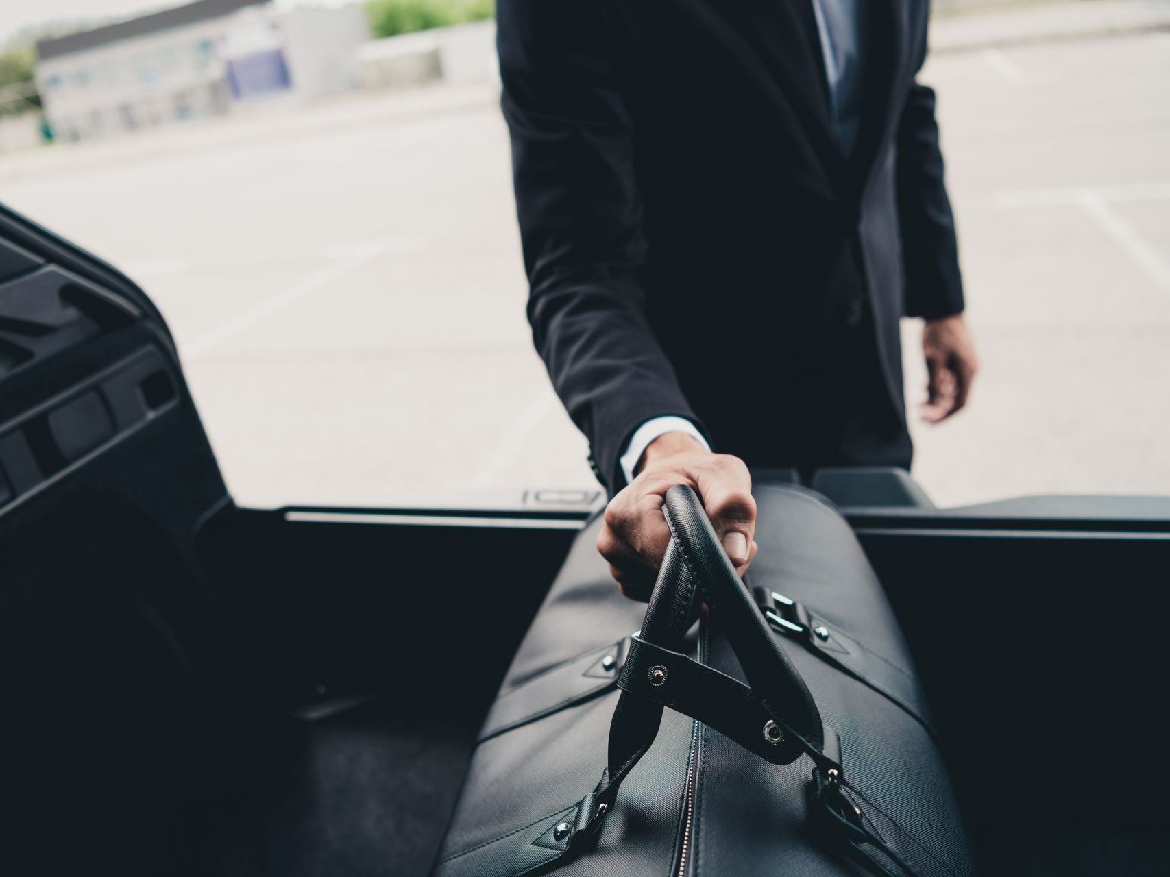 Homme en costume posant un bagage dans le coffre