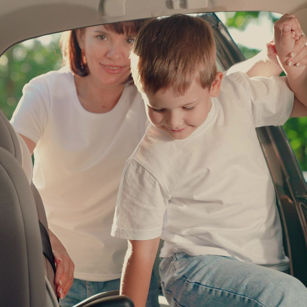 Une mère installant son enfant à l'arrière d'une voiture