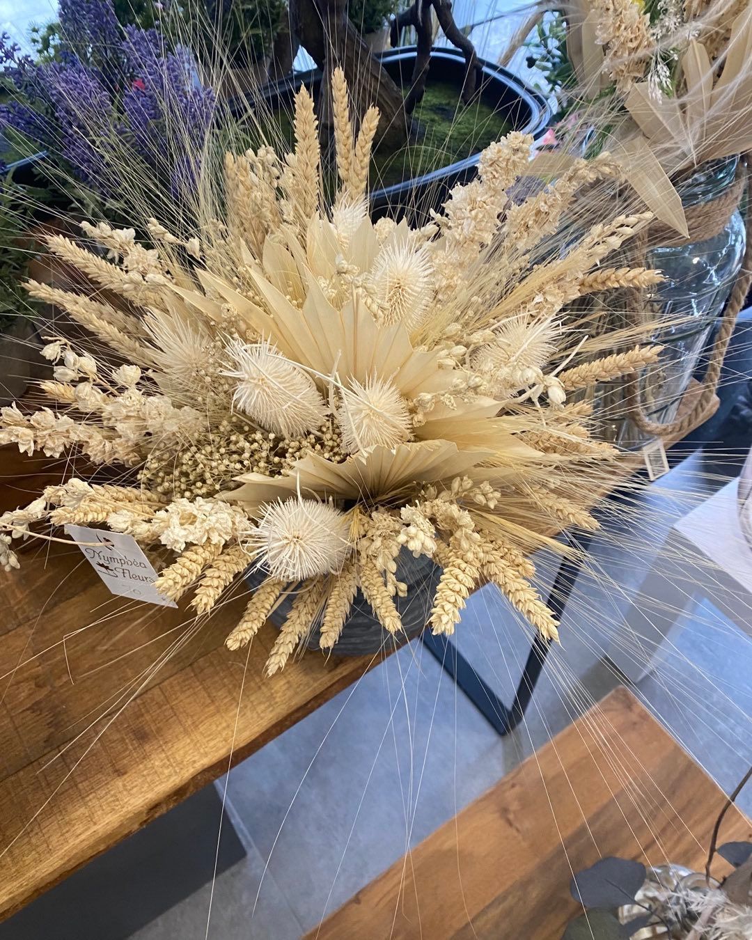 Composition de fleurs séchées dans les tons crème et beige sur une surface en bois.