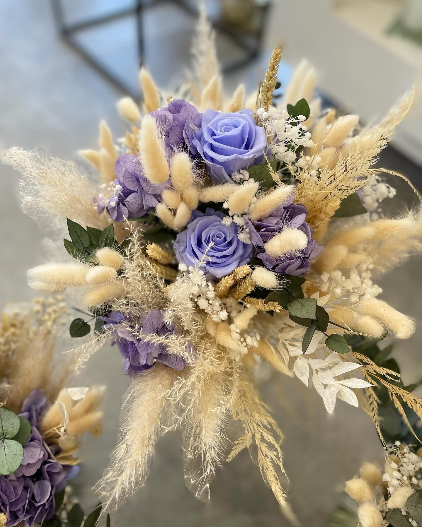 Bouquet de roses lavande, d'herbes de la pampa beiges et duveteuses, de gypsophile blanche et de feuillage vert.