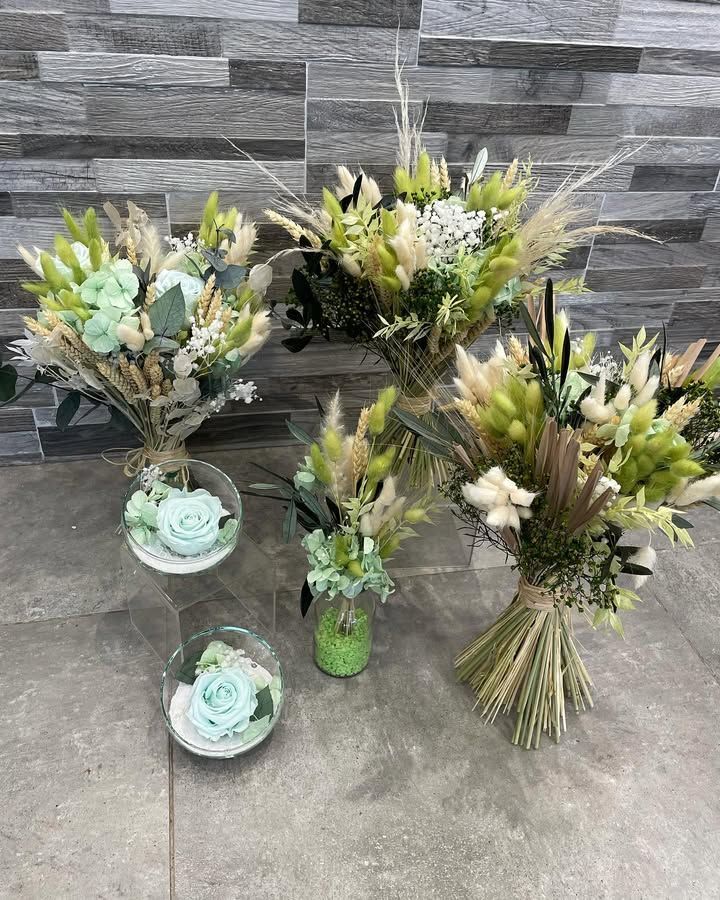 Composition de fleurs séchées dans les tons de vert et de beige. Certains bouquets sont dans des récipients en verre, et un autre est noué.