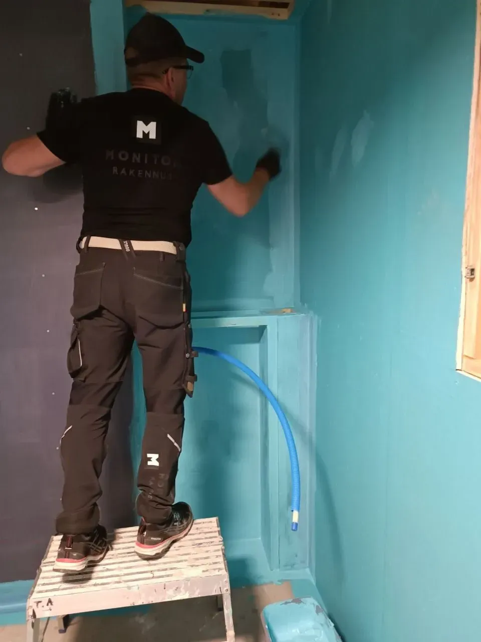 Rakennustyöntekijä maalaa seinää