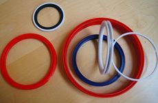 Auf einem Holztisch liegt eine Gruppe roter, blauer und weißer Gummiringe.