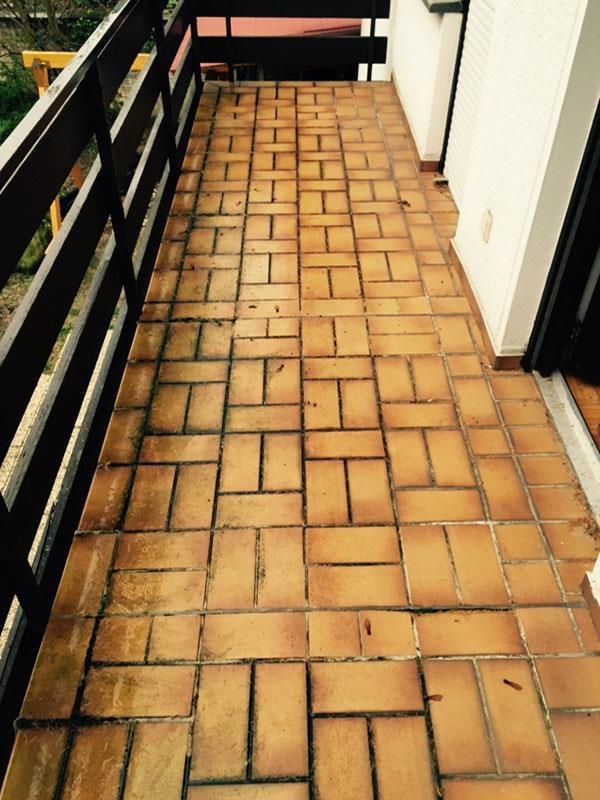 Ein Balkon mit braunen Fliesen und einem schwarzen Geländer