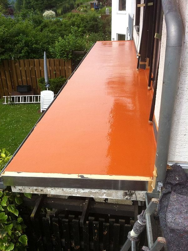 Ein orange gestrichener Balkon mit einer Leiter im Hintergrund